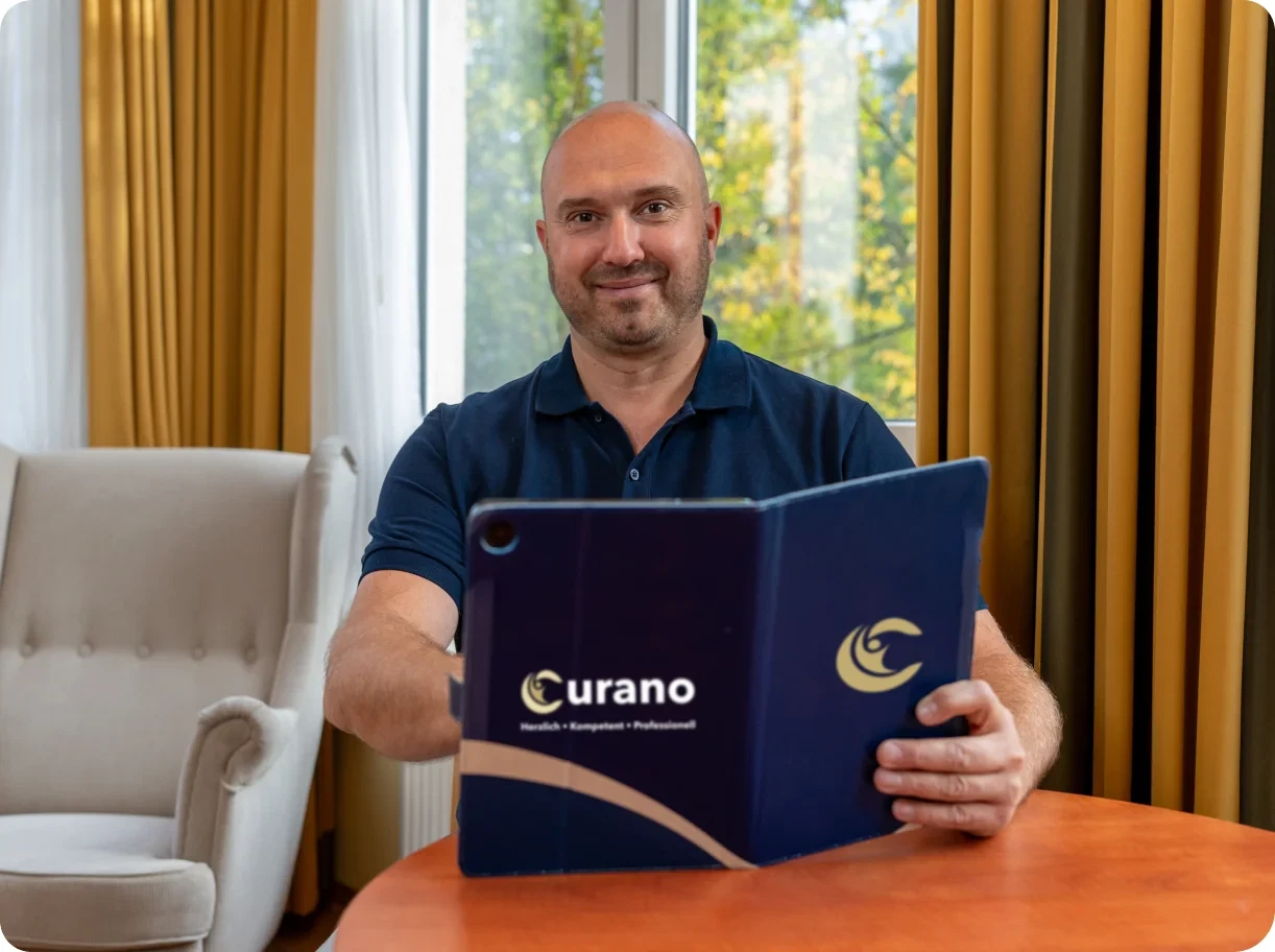 Therapeut mit einer Curano-Mappe an einem Tisch