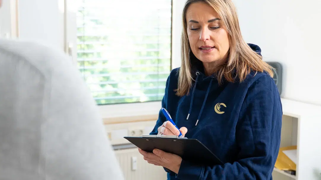 Therapeutin macht sich im Gespräch mit einem Patienten Notizen